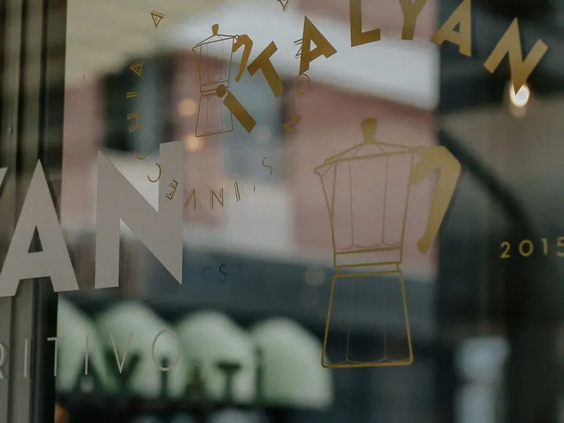 Goudkleurige letters en tekening op het raam van een café